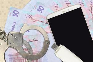 50 ukrainska hryvnias räkningar och smartphone med polis handklovar. begrepp av hackare nätfiske attacker, olaglig lurendrejeri eller skadliga program mjuk distribution foto