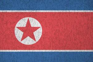 norr korea flagga avbildad i ljus måla färger på gammal lättnad putsning vägg. texturerad baner på grov bakgrund foto