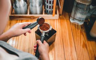 Barista häller kaffe böna rosten pulver jord kaffe häller in i en portafilter med en Barista hand på de kaffe affär foto