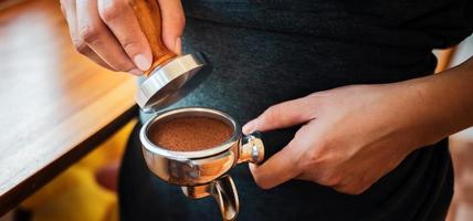 närbild av hand Barista Kafé framställning kaffe med manuell trycker på jord kaffe använder sig av manipulera på de kaffe affär foto