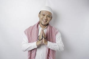 leende ung asiatisk muslim man, gestikulerar traditionell hälsning isolerat över vit bakgrund foto