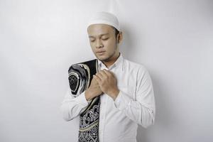 Lycklig stilig asiatisk muslim man med bön matta på hans axel är bön- till Gud. foto