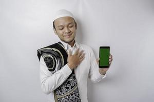 en porträtt av en Lycklig asiatisk muslim man leende medan som visar kopia Plats på hans telefon, isolerat förbi vit bakgrund foto