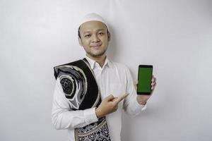 en porträtt av en Lycklig asiatisk muslim man leende medan som visar kopia Plats på hans telefon, isolerat förbi vit bakgrund foto