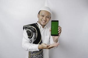 en porträtt av en Lycklig asiatisk muslim man leende medan som visar kopia Plats på hans telefon, isolerat förbi vit bakgrund foto