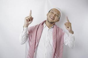 leende asiatisk muslim man pekande på de kopia Plats på topp av honom, isolerat förbi vit bakgrund foto