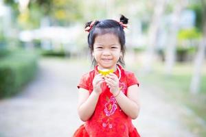 porträtt unge flicka var förtjust till håll gyllene. kinesisk ny år festival begrepp. ljuv leende barn bär röd cheongsam. barn är 5 år gammal. foto