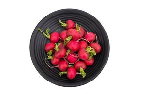 röd eller lila rädisor är placerad på en svart tallrik. organisk sallad, friska naturlig mat Ingredienser. isolerat på vit bakgrund, topp se - klippning väg foto