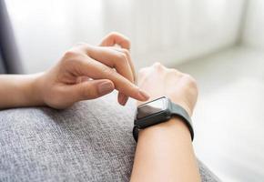 ung kvinna använder sig av smart klocka på henne handled foto