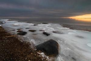 baltic hav kust med småsten och is på solnedgång foto