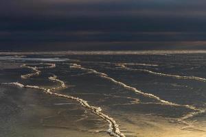 baltic hav kust med småsten och is på solnedgång foto