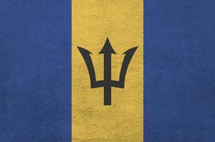 barbados flagga avbildad i ljus måla färger på gammal lättnad putsning vägg. texturerad baner på grov bakgrund foto