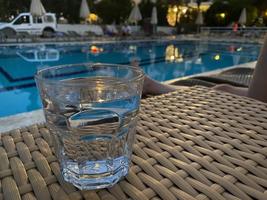 en glas med en klar alkoholhaltig utsökt dryck i främre av de slå samman i de kväll på semester i en tropisk tillflykt på de hotell foto