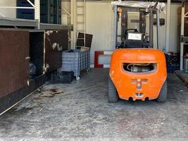 ett orange industriell gaffeltruck lastbil står i en garage för underhåll foto