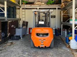 ett orange industriell gaffeltruck lastbil står i en garage för underhåll foto