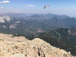 bak- se av ett person skärmflygning över bergen foto