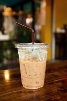 iced kaffe i en plast kopp med sugrör på en trä- tabell i en Kafé. foto