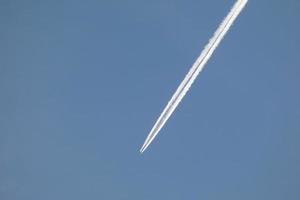 vit vakna av ett flygplan under de blå himmel foto