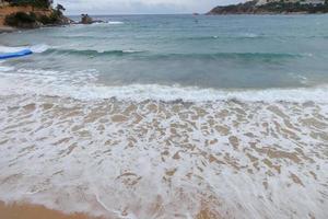 skum från de vågor som de nå de sand på de strand foto