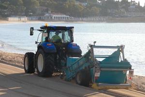 traktor rengöring de vit sand på de strand foto