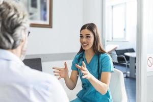 patient med läkare i sjukhus väntar rum diskuterar hans symtom. ung kvinna läkare talande med henne patient och förklara honom hans alternativ och terapi foto