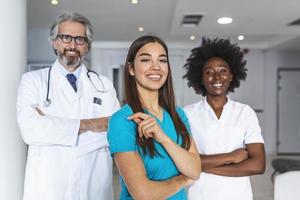 medicinsk yrkesverksamma stående tillsammans. begrepp av hälsa skydd. framgångsrik team av medicinsk doktorer är ser på kamera och leende medan stående i sjukhus foto