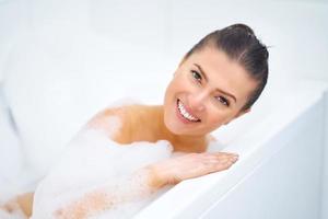 ung trevlig brunett kvinna har bad i badkar foto