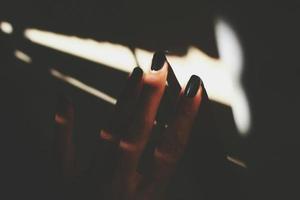 närbild av kvinnas hand med målad naglar i solljus foto