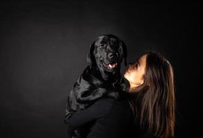 en flicka håller en labrador retrieverhund i famnen. foto