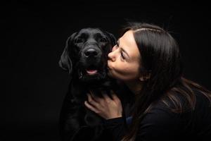 en flicka håller en labrador retrieverhund i famnen. foto