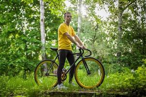 en ung man stannade för att vila med sin cykel i en allmän park. foto