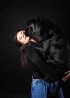 en flicka håller en labrador retrieverhund i famnen. foto