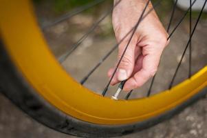 en ung man reparerar hjulet på sin cykel. foto