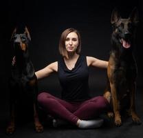 porträtt av en doberman hund och en belgisk herde hund med en flicka ägare. foto