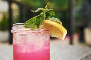 rosa färgad flytande med citron. stänga upp se av färsk sommar alkoholhaltig cocktail på de trä- tabell foto