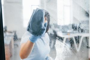kvinna rengöring smutsig fönster förbi använder sig av handduk. se genom de glas foto