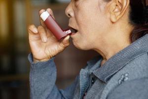 närbild kvinna senior patient användningar brun astma inhalator för lättnad astma. begrepp , hälsa vård på Hem. farmaceutisk Produkter för behandling symptom av astma eller copd. använda sig av under recept. foto