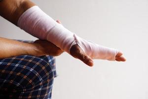 närbild hand insvept med bandage på vrickning handled, skada ärm behandling. begrepp, hälsa problem, olycka, först hjälpa. försäkring. foto