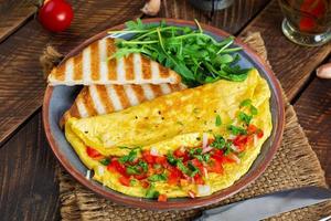 friterad omelett med tomater, lök och örter. utsökt frukost med ägg och skålar foto