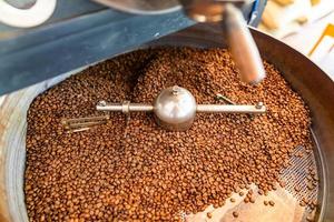 nyligen rostad aromatisk kaffe bönor i en modern kaffe rostning maskin. kaffe stekare, kaffe bönor bakgrund foto