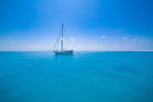 vit segling båt reser i maldiverna blå hav på en ljus solig sommar dag i de mitten av ingenstans. tropisk hav och segling båt. Nej segel upp i lugna hav foto