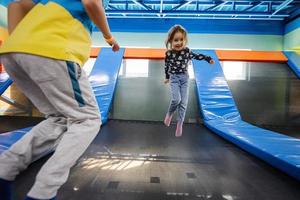 bror med syster spelar på inomhus- spela Centrum lekplats , Hoppar i trampolin. foto