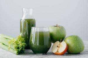 foto av grön smoothie med cerely och äpple i två glasbehållare på vit bakgrund. hälsosam ekologisk juice. bantning koncept.