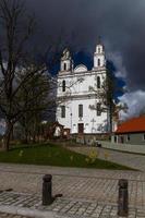 en vit katolik kyrka på en sommar dag med mörk moln i de bakgrund foto