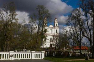 en vit katolik kyrka på en sommar dag med mörk moln i de bakgrund foto