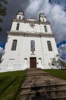 en vit katolik kyrka på en sommar dag med mörk moln i de bakgrund foto