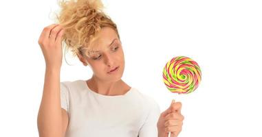 blond kvinna slick ljuv godis. kvinna modell äter utsökt konfektyr klubba med överraskad uttryck. foto