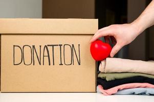 oigenkännlig manlig innehav hjärta nära donation låda och stack av kläder. portion människor. välgörenhet foto