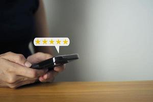 kvinna hand använder sig av smartphone med fem stjärna dyka upp ikon tillfredsställelse undersökning begrepp företag kund service. foto