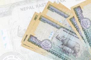 100 nepalesiska rupier räkningar lögner i stack på bakgrund av stor halvtransparent sedel. abstrakt presentation av nationell valuta foto